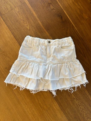 Vit volangkjol denim XS Gina tricot ny  - Supersöt vit kortkjol med dubbla volanger och råa kanter för en avslappnad look. Kjolen har fickor fram, knapp och hällor i midjan. 