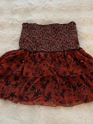 Röd blommig volangkjol från Zara - Supersöt kort kjol från Zara i röd nyans med blommigt mönster och volanger. Knappt använd så bra skick, perfekt nu till sommaren. OBS LÅNADE BILDER