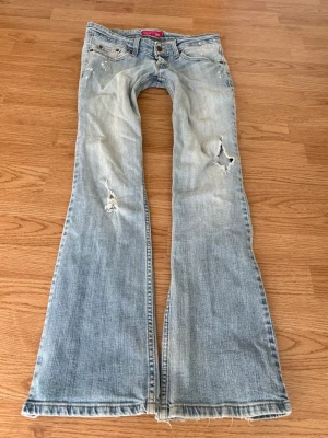 Vintage superlågmidjade bootcut jeans från Levi’s - Sååå sjukt snygga ljusblå superlågmidjade vintage jeans med slitna detaljer från Levis! Står superlowwaist bootcut på lappen i ❤️ Innebenslängd: 84 cm Midjemått rakt över: 38 cm