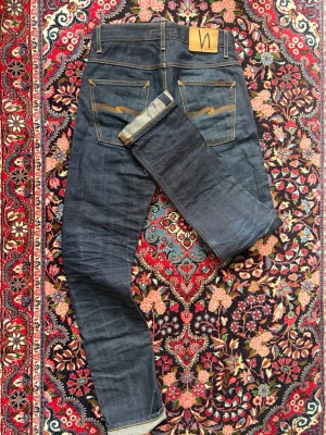 Nudie dry selvedge Jeans - Nudie dry selvedge Jeans | passform: Grim Tim / slim fit | storlek: w29/L32 | Storleks lappar saknas men midjan: 79cm & inside leg: 86cm | Skick: mycket bra, de har knappt blivit tvättade/använda vilket betyder att de inte fått någon fade, så du kommer få en egen fade desto mer du har på dig och tvättar jeansen.