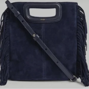 Mörkblå mocka axelväska från Maje - Snygg mörkblå axelväska i mocka från Maje med fransar på sidorna och stilrent handtag upptill. Väskan har en justerbar axelrem och en fyrkantig form som ger en cool och modern vibe.