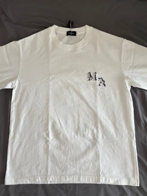 Vit t-shirt med tryck   - Vit t-shirt med svart/mörkgrå tryck på ryggen och bröstet. Perfekt till sommaren. M, sitter mer som S. Pris går att diskutera. 
