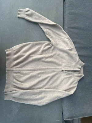 Beige ziptröja från EVSEG - Stilren beige ziptröja från EVSEG i mjukt material. Tröjan har hel dragkedja framtill, ribbade muddar och hög krage. Exklusiv handgjord tröja.  100% äkta kashmir - mjuk, varm o mysig  Beige färg som passar allt   Unik kvalitet som ej finns i butik  Perfekt för vardag och jobb