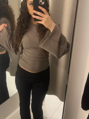 Brun långärmad   - Snygg brun långärmad topp med croppad passform och rund halsringning. Toppen är tight och har en enkel, stilren design som passar perfekt till jeans eller kjol.