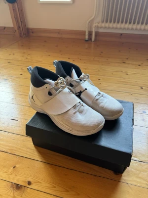 Vita Jordan - Snygga vita Jordan sneakers med svart logga på sidan och svart insida. Skorna har både snörning och ett brett kardborreband över vristen för extra support. Storlek US 10,5 (EU 44,5)