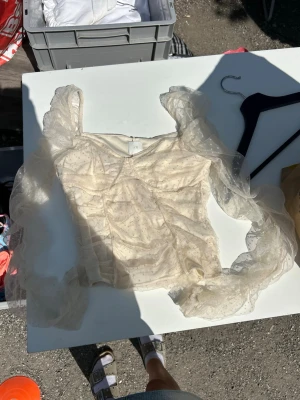 Vit topp från H&M - Säljer en söt vit blus från H&M med transparenta puffärmar och volangdetaljer. Toppen har små prickar i tyget och en lätt v-ringning. Perfekt för dig som gillar romantisk och trendig stil.