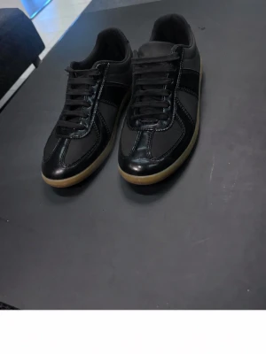 Svarta maison margiela med gummisula - Snygga svarta maison margiela  med ovandel i läder och detaljerade sömmar. 