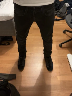 Svarta Replay jeans  - Säljer ett par svarta slim fit jeans från Replay då de är lite små på mig. Jeansen har en modern passform och är tillverkade i mjukt denimtyg med lite stretch för extra komfort. Köptes online på Boozt om jag minns rätt.