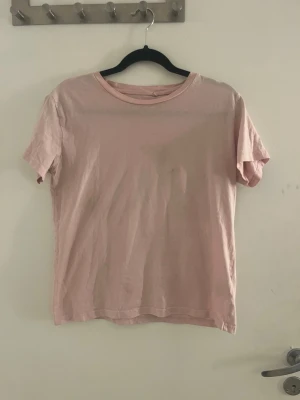 Ljusrosa basic t-shirt i bomull - En enkel och stilren ljusrosa t-shirt med rund hals och korta ärmar. Tillverkad i mjuk bomull som känns skön mot huden. Perfekt att matcha med jeans eller kjol för en avslappnad look.