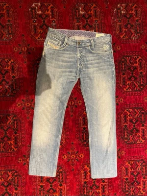  Raka Disel Jeans - Säljer ett par ljusblå Disel jeans med raka ben och diskreta slitningar på fickorna. Jeansen har klassisk femficksmodell, normal midja och är tillverkade i denim med snygg tvättad look. Perfekta för en avslappnad stil. Om du undrar något är det bara att skriva🙌