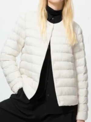 Uniqlo - jacka beige  - Säljer en vit dunjacka med quiltad design och rund hals. Jackan har en clean, minimalistisk look utan synliga fickor eller dragkedja framtill. Perfekt för dig som gillar stilrena plagg och vill hålla värmen under vintern.
