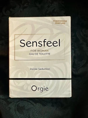 Sensfeel Eau de Toilette för kvinnor - Sensfeel Eau de Toilette för kvinnor från Orgie är en parfym med feromoner som ska framkalla attraktion. Förpackningen är vit med subtila mönster och guldiga detaljer. Doften kommer i en 50 ml sprayflaska och har en modern, elegant design.