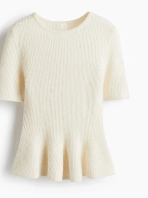 Krämvit stickad topp med volang - Supersöt krämvit stickad topp med korta ärmar och volangkant nedtill. Rund halsringning och mjukt material som känns lyxigt mot huden. Perfekt för dig som vill ha en enkel men ändå unik topp i garderoben.