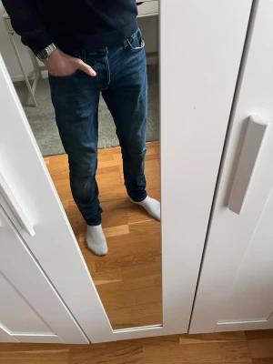 Mörkblå slim fit jeans - Säljer nu ett par riktigt schyssta mörkblå slim/glen fit jeans från Jack&Jones. Jeansen är i toppskick och är otroligt bekväma. Storleken är 32/34. Tveka inte på att höra av dig innan du köper den ifall du har några funderingar! Pris kan diskuteras!
