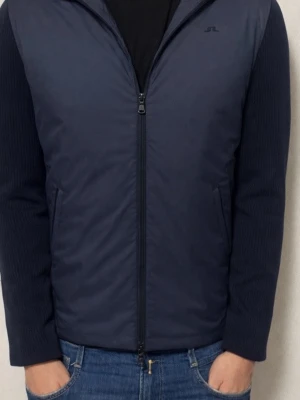 J.Lindeberg Cardigan - Snygg marinblå hybridjacka från J.Lindeberg med stickade ärmar och huva. Jackan har dragkedja framtill och två sidofickor. Kroppen är quiltad i polyester medan ärmarna är ribbstickade för extra komfort. Perfekt för dig som vill ha en sportig och stilren look.