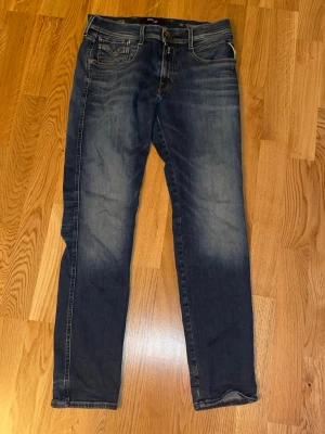 Mörkblå jeans från Replay - Säljer ett par mörkblå jeans från Replay med snygga slitningar och klassisk femficksmodell. Jeansen har raka ben och kontrastsömmar, tillverkade i denim med en skön känsla. Perfekta för dig som gillar en avslappnad men stilren look. Helt klart ett par lite sjystare jeans 
