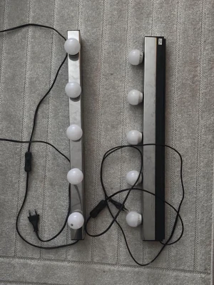 Sminkspegelbelysning med LED-lampor - Säljer två sminkspegelbelysningar med fyra runda LED-lampor vardera. Lamporna sitter på en lång, rektangulär list i silverfärgat material med svart baksida. Perfekt för att få bra ljus vid sminkning. Ansluts med sladd och strömbrytare.