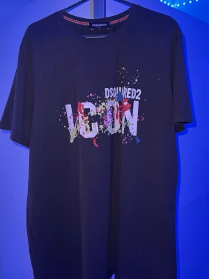  Dsquared2 ICON t-shirt passar som S och m  - Snygg svart t-shirt från Dsquared2 med stort vitt 'ICON'-tryck och färgstänk i flera nyanser på bröstet. Klassisk rund hals och korta ärmar. Perfekt statement-plagg för dig som gillar streetwear och vill sticka ut.