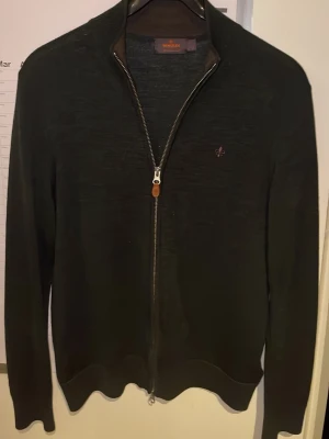 Mörkgrön zipup från Morris - Stilren mörkgrön fullzip från Morris. Tröjan har hög krage, hel dragkedja och ribbade muddar vid ärmslut och nederkant. Perfekt till lager på lager och enkel att matcha med olika outfits. Nypris på 2000