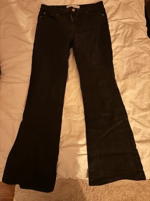 Svarta bootcut jeans  - Snygga svarta jeans med bootcut-modell och utsvängda ben. Klassisk femficksdesign och knappgylf. Perfekta för dig som gillar en retroinspirerad look och vill ha ett par jeans som sticker ut lite extra.