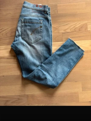 Blå jeans med broderad bakficka - Snygga blå jeans i klassisk modell med broderad detalj på bakfickan. Jeansen har normal midja, raka ben och är tillverkade i denim. Perfekta för en avslappnad och trendig look.