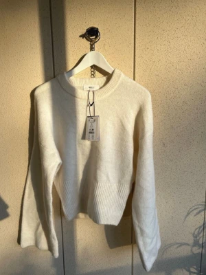Vit wide sleeve knitted sweater från Gina - Mysig vit stickad tröja med rund halsringning och bred ribbstickad kant nedtill. Tröjan har långa ärmar och är wide sleeve. Helt ny med lappar 