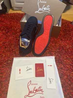 Svarta Mörkblåa  från Christian Louboutin - Snygga mörkblå sneakers från Christian Louboutin med klassisk röd sula och diskret logga på sidan. Skorna är låga och har ovandel i mocka med matchande svarta skosnören. Kommer med originalkartong, dustbag och certifikat.  HELT OANVÄNDA, Våga att skriva  