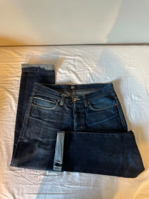 Mörkblå selvedge jeans - Snygga mörkblå jeans från Neuw med klassisk femficksdesign och raka ben. Jeansen har kontrastsömmar och är tillverkade i ett slitstarkt denimtyg. Perfekta för dig som gillar en stilren och tidlös look.