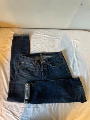 Mörkblå selvedge jeans - Säljer ett par mörkblå jeans från Neuw med klassisk femficksdesign och raka ben. Jeansen har kontrastsömmar och är tillverkade i ett slitstarkt denimtyg. Perfekta för dig som gillar en tidlös och clean look.
