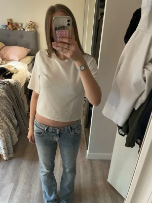 Vit topp från Nelly - En enkel och stilren vit topp från Nelly. Modellen har rund halsringning och korta ärmar, perfekt för en clean och avslappnad look. Passformen är normal och toppen är lätt att matcha med olika outfits.