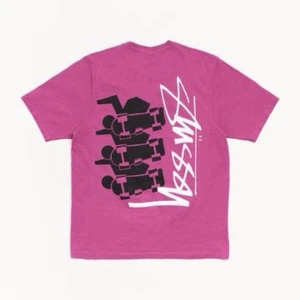 Rosa Stüssy t-shirt med grafiskt tryck - Helt ny - Oanvänd!  Cool rosa t-shirt från Stüssy med stort grafiskt tryck i svart och vitt på ryggen. Klassisk passform och rund halsringning, perfekt för en streetwear-look.