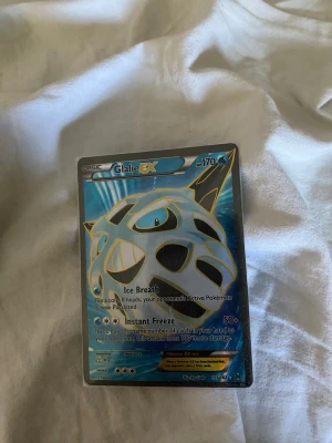 Glalie EX Pokémonkort - Säljer ett Glalie EX Pokémonkort med blå och silver holografisk design. Kortet har 170 HP och attacker som Ice Breath och Instant Freeze. Perfekt för samlare eller Pokémonfans som vill utöka sin kortsamling.