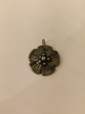 Blomformad halsbandsberlock i mörk silverfärg - Säljer en vintage blomformad halsbandsberlock i silverfärgad metall. Perfekt att hänga på en kedja för ett halsband. 