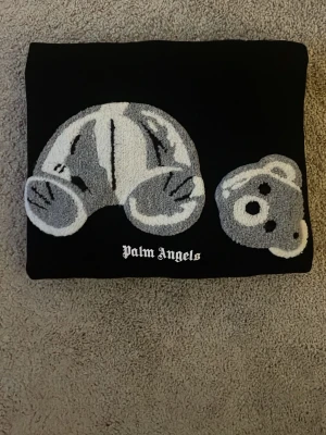 Palm Angels svart hoodie med björn - Svart hoodie från Palm Angels med stort broderat motiv av en isärplockad nallebjörn i grått och vitt på bröstet. Klassisk huva och ribbade muddar. Ikonisk streetwear-stil med tydlig logga under motivet. Perfekt för dig som gillar trendiga och unika plagg.