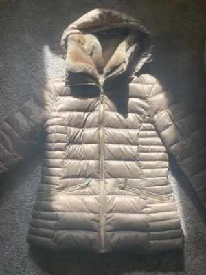Brun Micheal kors jacka - Väldigt snygg brun micheal kors jacka i storlek S. Fluff i luvan och 4 fickor, två vid magen och varsinn på varenda ärm.