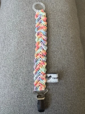 Virkad napphållare  - Virkad, multifärgad napphållare i pastellfärger. Virkad av mig i 100% bomullsgarn med metallclip och silikonring.  Mönsterskapare: animo.design