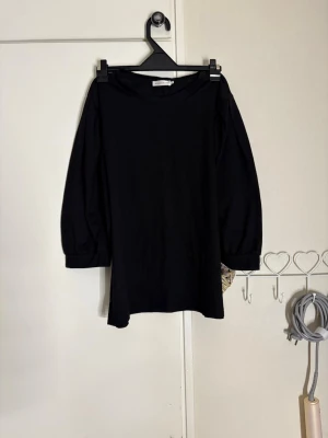 Svart topp med trekvartsärm från Vero Moda - En svart topp från Vero Moda med trekvartsärmar och rund halsringning. Modellen är loose fit och har en enkel, stilren design som passar till många olika outfits. Perfekt för dig som gillar en avslappnad men ändå trendig look.