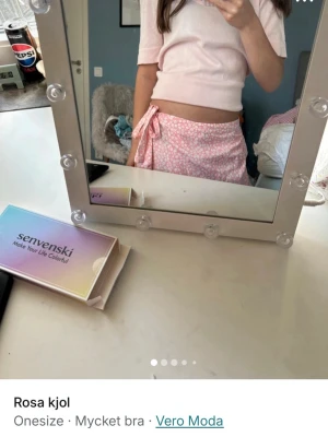 Rosa omlottkjol från Vero Moda - Supersöt rosa omlottkjol från Vero Moda med vitt blommönster och knyt i midjan. Kjolen är kort och har en lätt och luftig känsla, perfekt för varmare dagar. Onesize och passar de flesta.