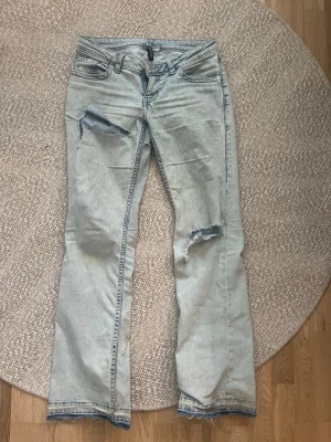 Ljusblå slitna jeans från H&M Divided - Säljer ett par jeans som är välanvända, har klippt egna hål som passar jeansen bra🌸 Som referens jag är 175 och de passar perfa i längd💗 De har lite smuts längst ner från regn kommer såklart tvätta de ifall nån köper innan jag skickar!!