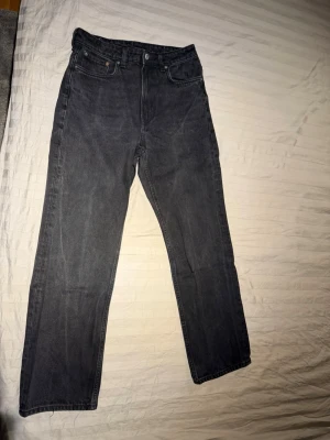 Svarta Weekday jeans - Snygga washed svarta weekday voyage jeans med rak passform och klassisk femficksdesign. Jeansen har hög midja och är tillverkade i ett robust denimtyg. Perfekta för en avslappnad och trendig stil. W29 L32 men passar mer L31. Mycket bra skick