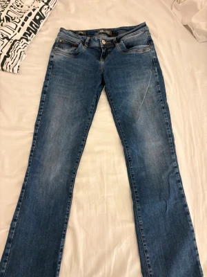 Blå bootcut jeans från LTB - Säljer ett par blå bootcut jeans från LTB, modell Valerie. Jeansen har klassisk femficksdesign, snygga slitningar och kontrastsömmar. Perfekta för dig som gillar en avslappnad men ändå trendig look. w27 l34
