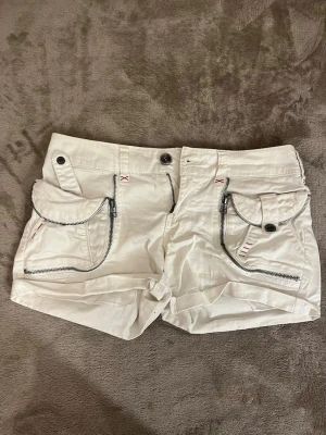 Lågmidjadr shorts  - Lågmidjadr vita 2000’s shorts, tröjan på bilden säljs också och väskan separat i andra annonser i min profil🥰 skriv för frågor eller bilder med kläderna på