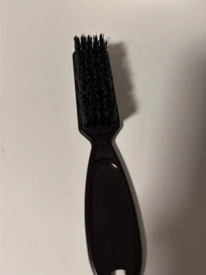 Svart hårborste med smalt handtag - En svart hårborste med smalt handtag och täta borststrån, perfekt för att styla babyhår eller skapa släta frisyrer. Tillverkad i plast med borst i syntetmaterial. Enkel och smidig att använda för detaljerad styling.