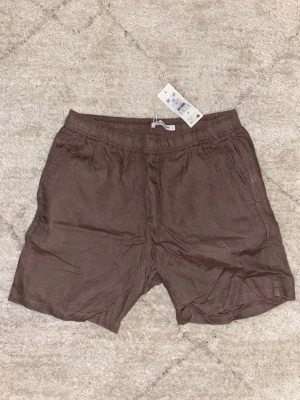 Bruna linneshorts från Samsoe Samsoe - Säljer ett par bruna shorts från Samsoe Samsoe i  linne. Storlek M. Aldrig använt (glömde att returnera). 