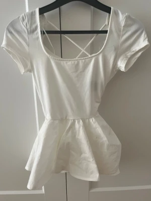 Vit kortärmad klänning med korsad rygg - Söt vit klänning i bomull med korta ärmar och rundad urringning. Toppen är utställd och har korsade band i ryggen. Storlek xs från h&m.