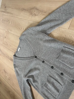 Grå kofta från John Henric - Snygg kofta från John Henric. Säljer pga att jag helt enkelt växt ur den. Materialet är otroligt skönt och bekvämt merinoulls material. Koftan är i ett bra skick med en minimal defekt som jag gärna skickar bild på. Storlek S, skriv gärna vid frågor! 