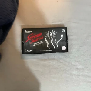 Svarta Scream Shots från Fiableeee - Säljer en låda med Scream Shots från Fiable. Svarta cylindriska tuber med röd och vit text samt grafiska mönster på förpackningen. Perfekt för dig som gillar unika och spännande produkter. Lådan innehåller flera tuber..