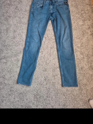 Blå raka jeans från replay - Säljer ett par klassiska blå jeans från Armani med rak passform och fem fickor. Jeansen har en snygg tvättad look och diskret logga på fickan. Perfekta till en avslappnad stil och tillverkade i mjukt denimtyg.