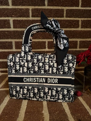 Svart vit väska  - Elegant broderad tote bag säljes, inspirerad av den klassiska book tote-stilen. Rymlig, stilren och superfin till både vardag, resa eller som statement-accessoar. Den strukturerade formen ger ett exklusivt intryck och lyfter en enkel outfit direkt.  I mycket fint skick, utan synliga tecken på användning. Säljes vidare då den inte kommer till användning ✨