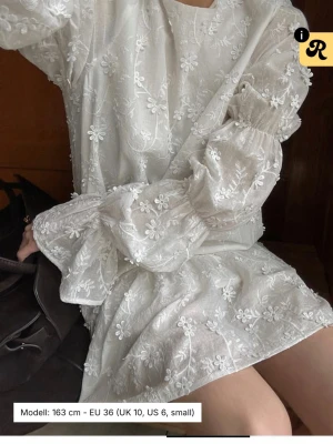 Vit blommig kortklänning med volang - Supersöt vit kortklänning med broderade blommor från NA-KD nypris 700kr. Använd fåtal gånger. Perfekt skolavslutningskläning. Skriv för egna bilder 